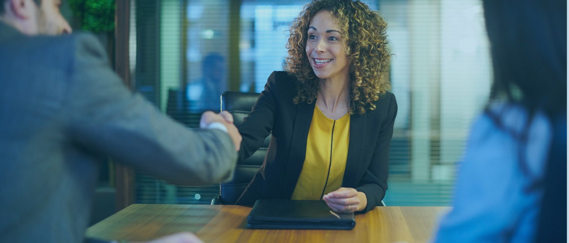 smiling woman in office attire shaking hands with man in a suit