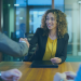 smiling woman in office attire shaking hands with man in a suit