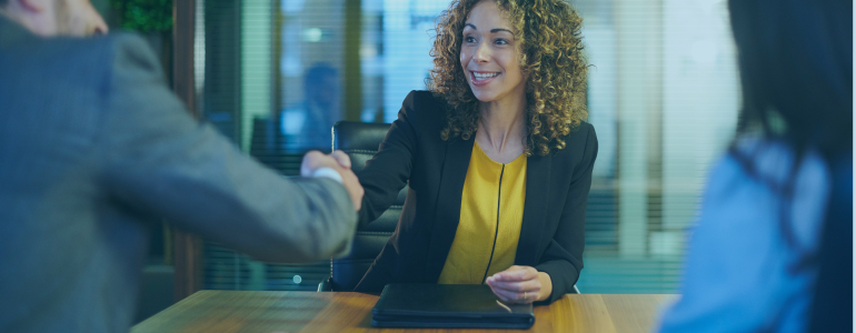 smiling woman in office attire shaking hands with man in a suit