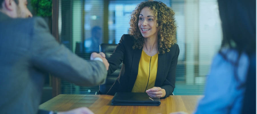 smiling woman in office attire shaking hands with man in a suit